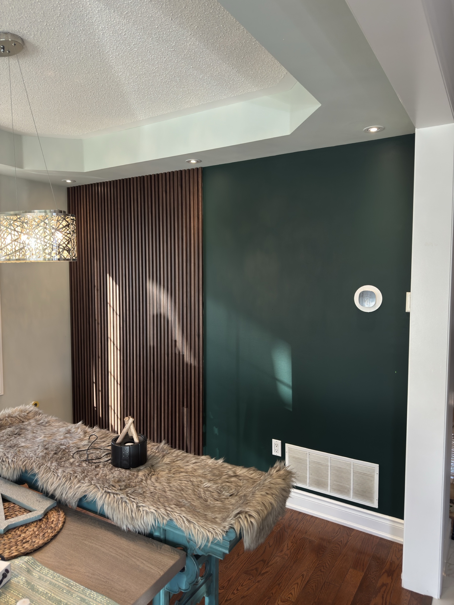 Deep green feature wall with a full-height section of warm vertical wood slats