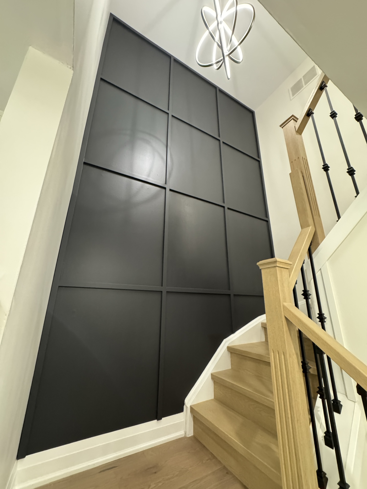 Black grid-panel accent wall beside a modern staircase