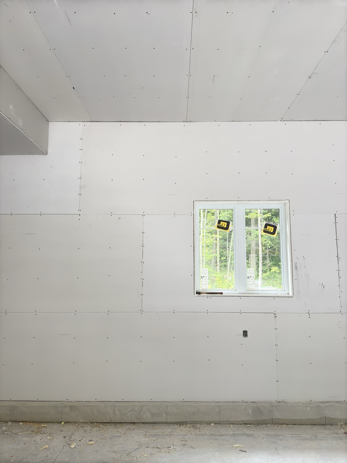 Full-height drywall installation around a window opening