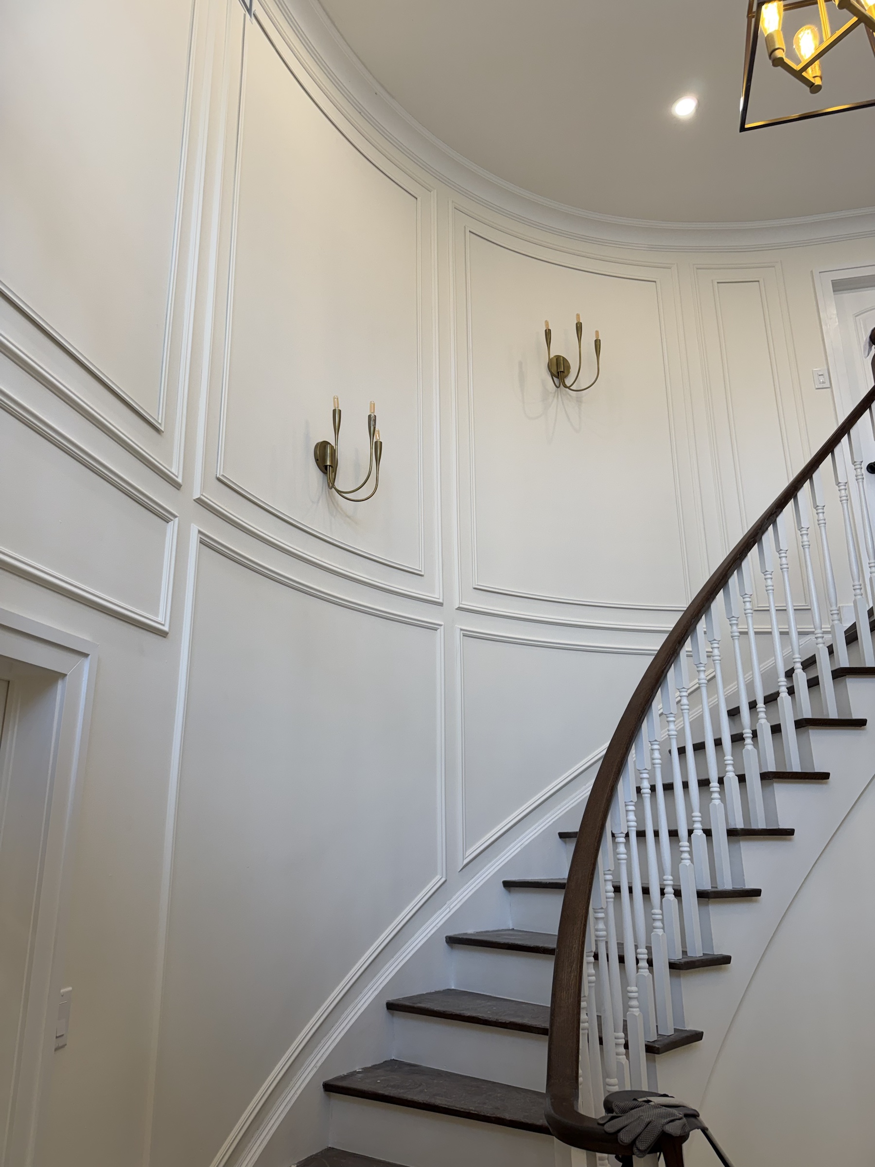 Full-height white panel moulding following a curved staircase